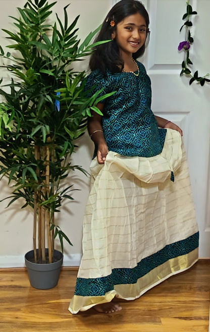 Girl twirling in teal ajrakh print top and cream Kerala kasavu skirt with teal gold border